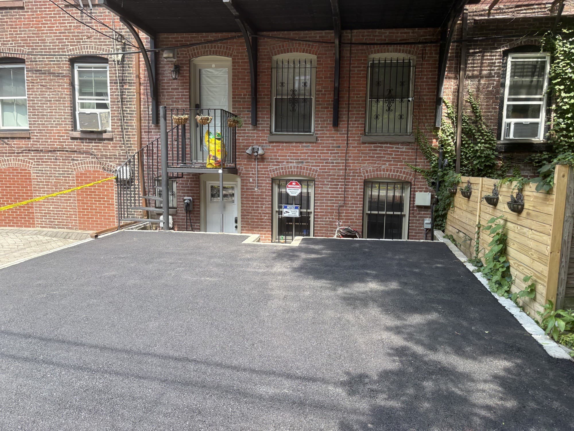 Finished asphalt driveway behind a brick building